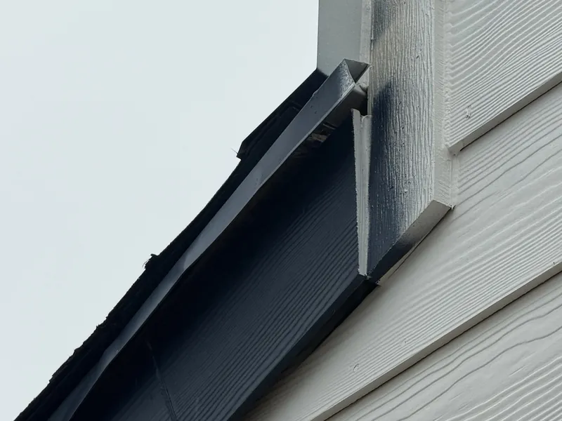 Roof edge flashing ending at the siding where the roofline meets the wall of a new home
