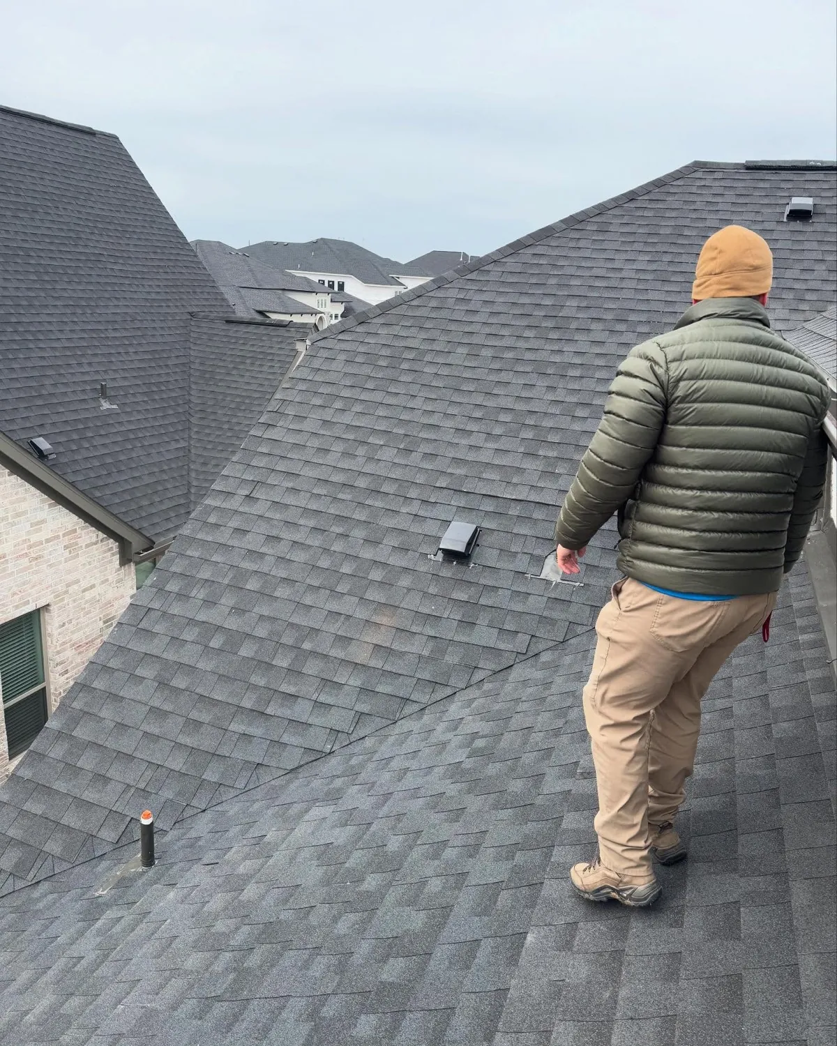 An A-Action inspector walking a composition-shingle roof during an inspection