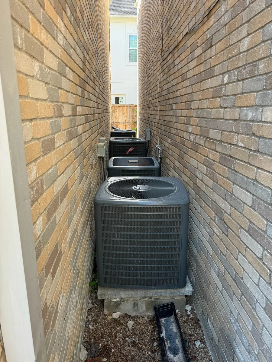 A row of outdoor AC condenser units between two brick walls, checked during a phase inspection