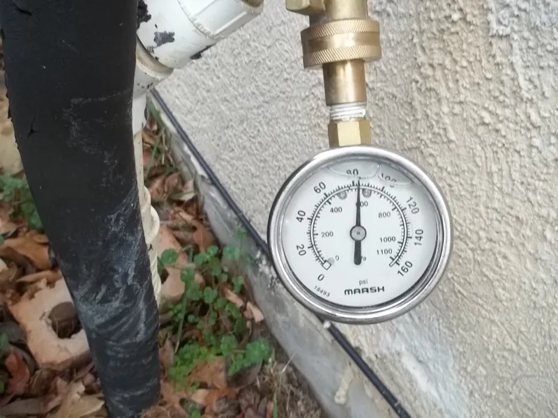 A water pressure test gauge attached to an exterior faucet